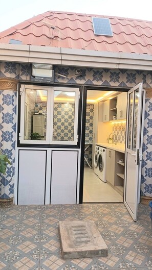 A laundry facility with a tiled floor, a washing machine, and a drying rack. - A charming apartment in the annex for a peaceful stay (Conakry)