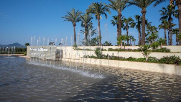 Een waterpartij met palmbomen en een bord met daarop 'Rincón del Mar' op de achtergrond.