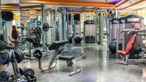 Un gimnasio con diverso equipo de ejercicio, que incluye máquinas de pesas, pesas libres y máquinas de cardio.