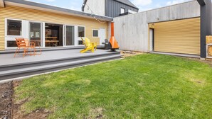 Una casa moderna con patio, puertas corredizas de vidrio y una parrilla.