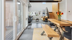 Un interior moderno con una mesa de comedor de madera, sillas negras y una lámpara colgante grande.