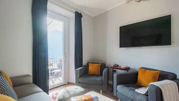 Una sala de estar moderna con sofá, sillón, reposapiés, televisor de pantalla plana y un tablero de ajedrez.
