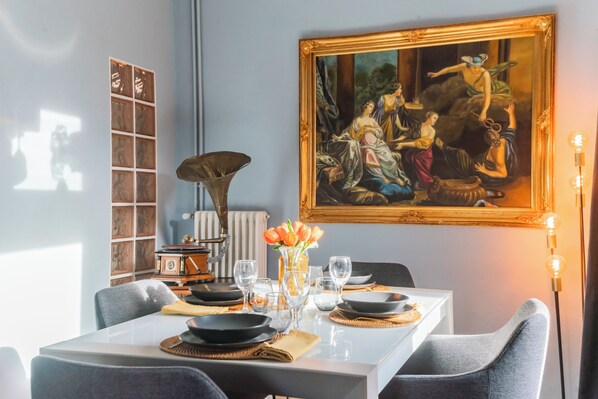 A dining area with a table set for four, a classical painting, and a vintage radio. - Villetta Panebianco Home in Castagna 11 by Rent all Como (Nesso)
