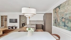 Un comedor moderno con una mesa blanca, sillas marrones y un florero con flores.
