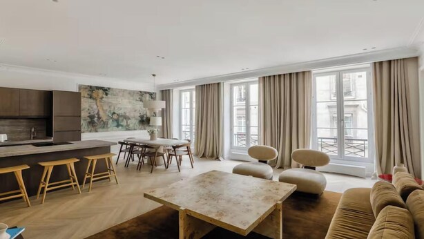 Una sala de estar moderna con comedor, ventanas grandes y una cocina.