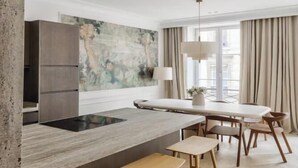 Una cocina moderna con una isla central, taburetes de bar y un comedor con mesa y sillas.
