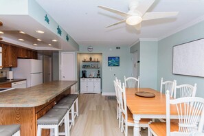 A modern kitchen with white cabinets, a wooden island, and a dining area with white chairs and a wooden table.
