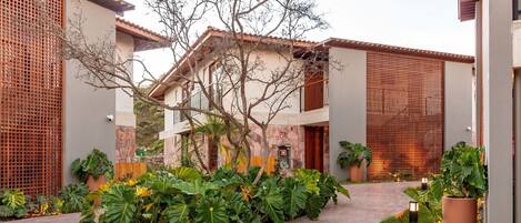 A courtyard with a central pathway, surrounded by lush greenery and potted plants.