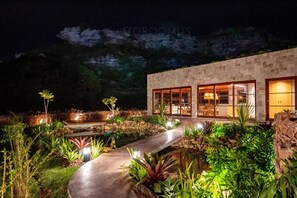 A modern building with large windows, a pathway, and a water feature. - Lar Aconchego Luxo do Diamantino Mucugê (Mucuge)