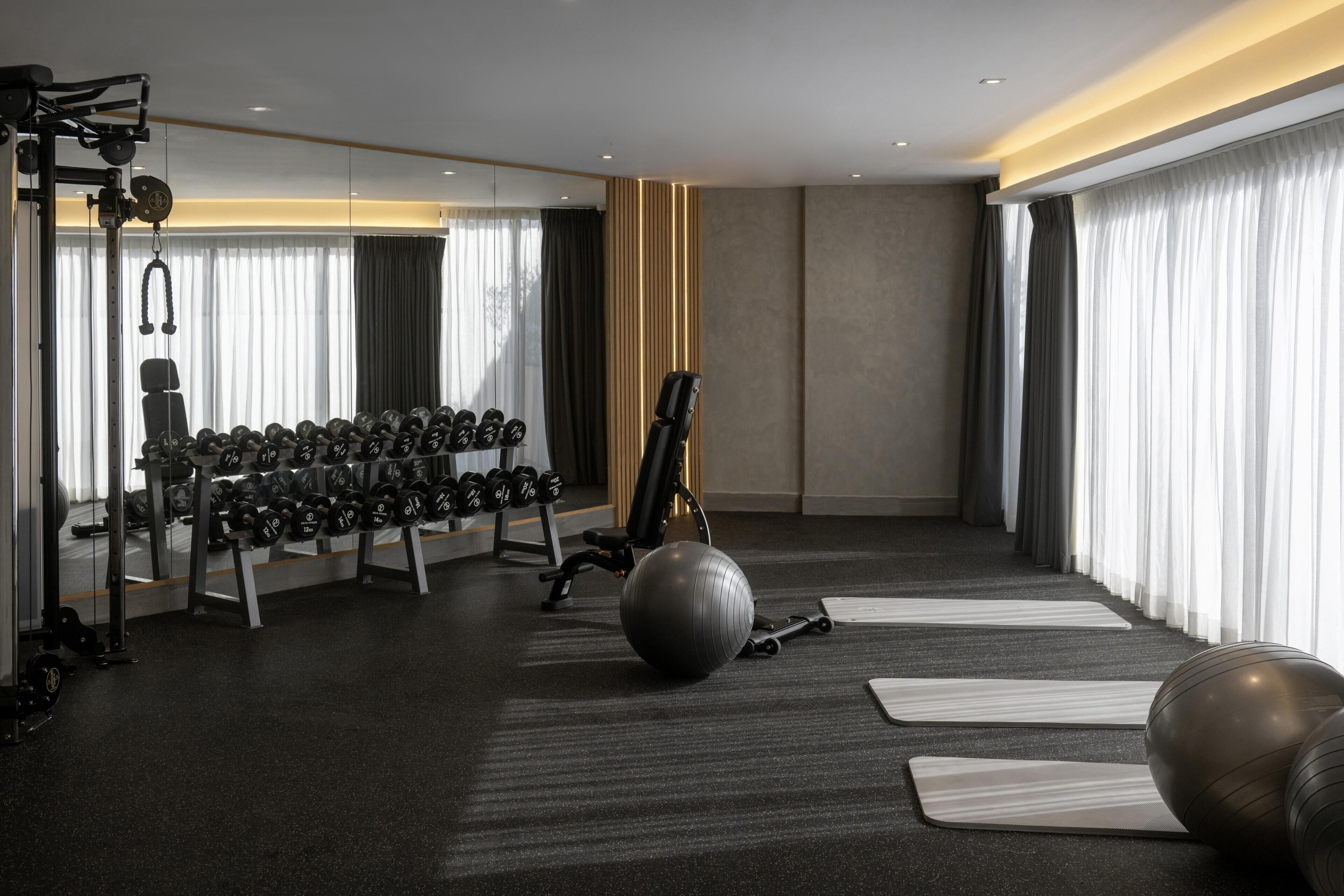 Uma academia moderna com equipamentos de ginástica, tapetes de yoga e uma grande bola de exercícios.