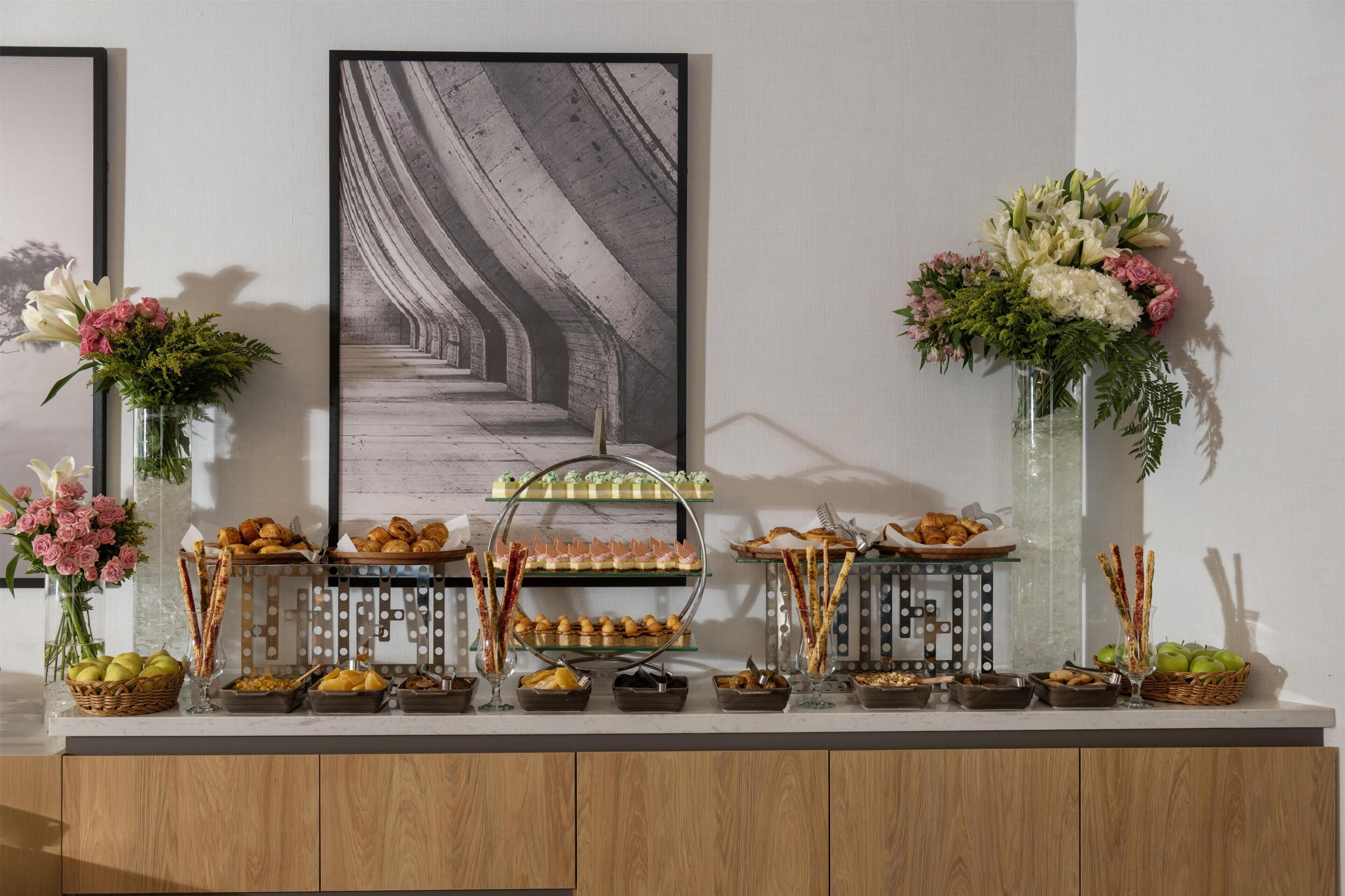 A buffet setup with various food items and floral arrangements.