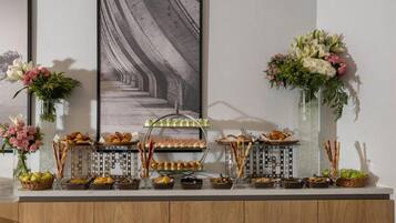 A buffet setup with various food items and floral arrangements.