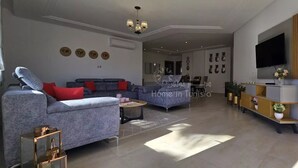 Ein modernes Wohnzimmer mit grauem Sofa, einem Couchtisch und einem an der Wand montierten Fernseher.