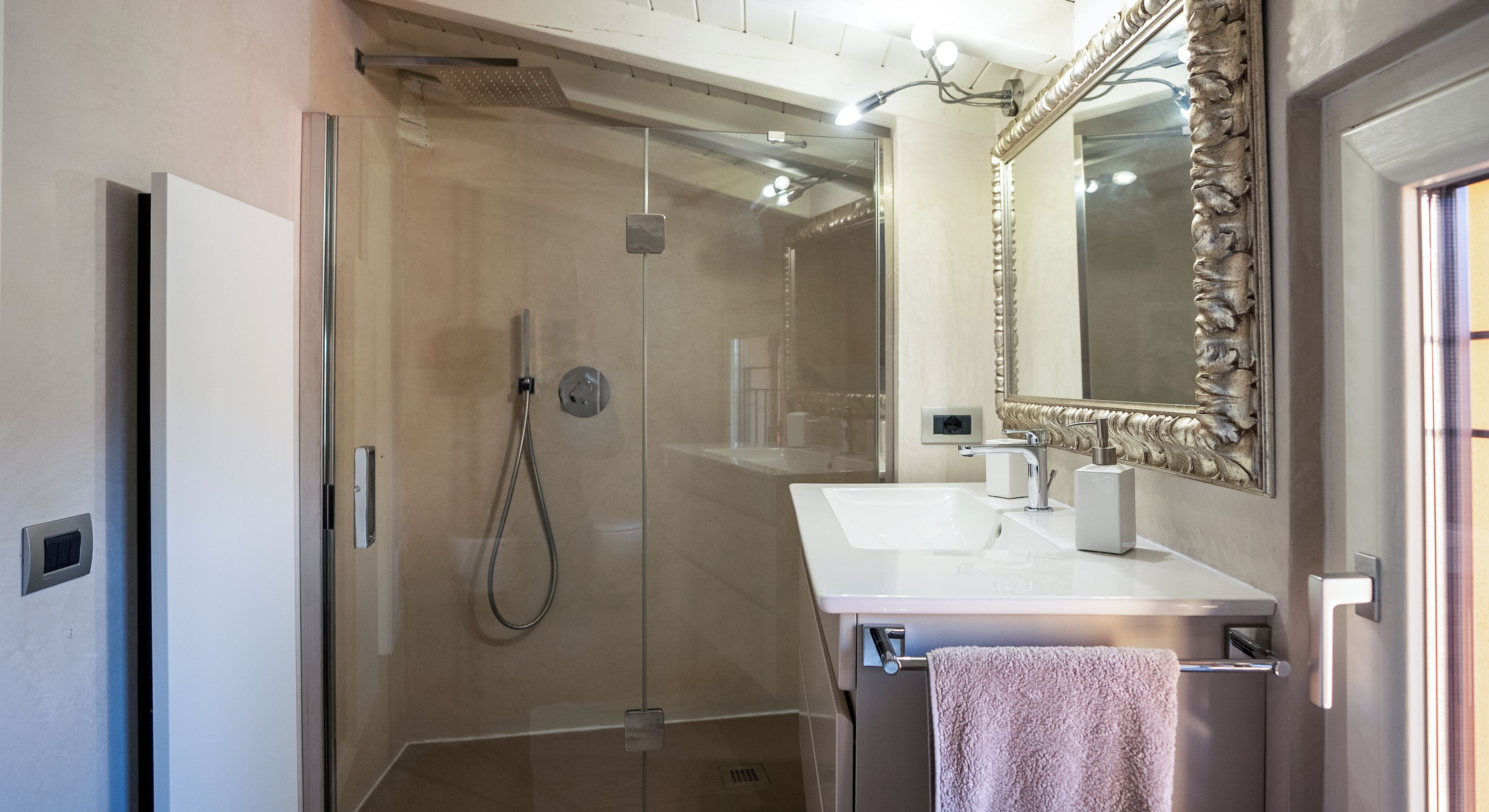 Une salle de bain moderne avec une douche à parois de verre, un lavabo blanc et un grand miroir décoratif.