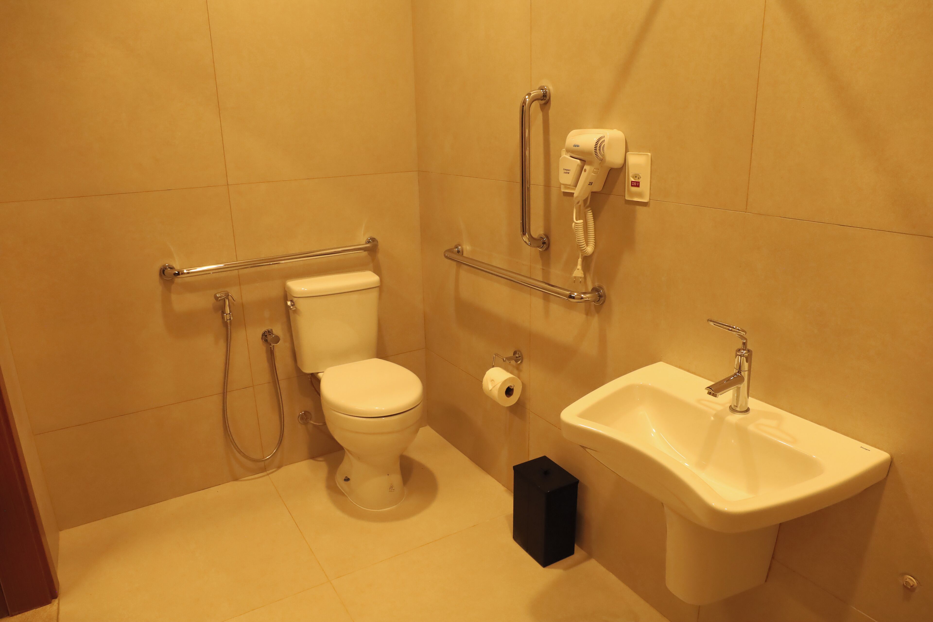 A bathroom with a toilet, bidet, hand dryer, and sink.