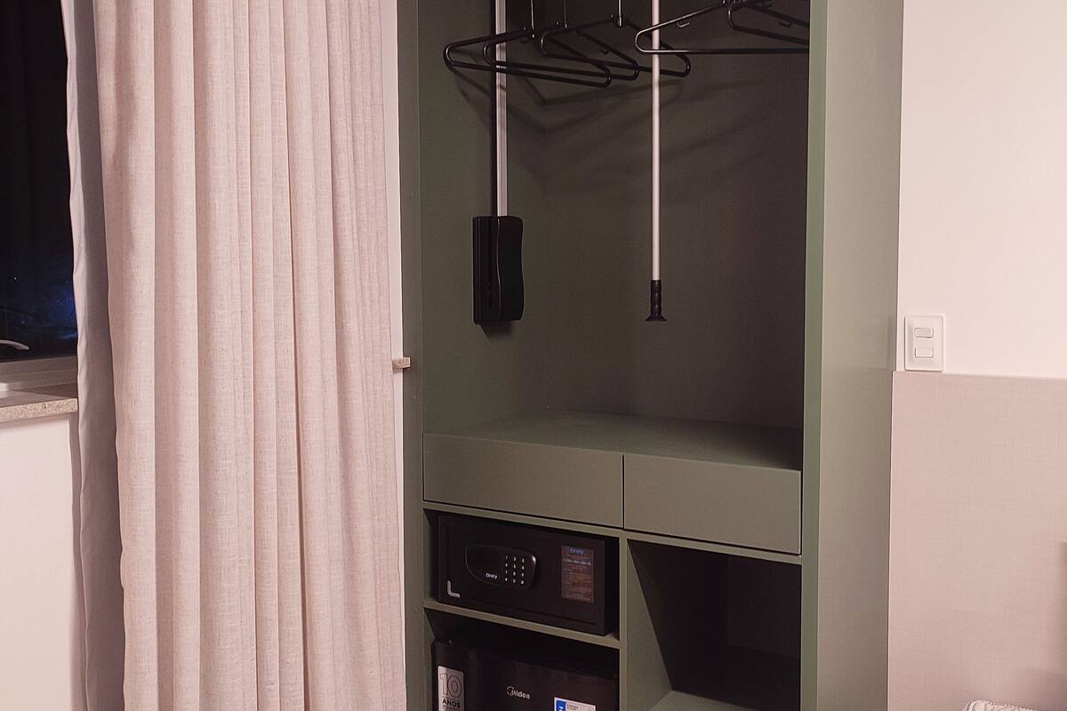 A room with a built-in wardrobe, a microwave, and a hanging rack.