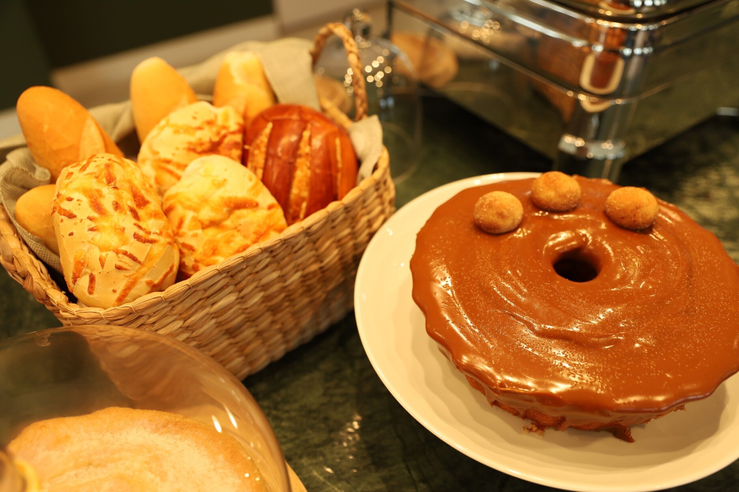 A basket of bread and a plate with a glazed donut.