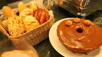 A basket of bread and a plate with a glazed donut.
