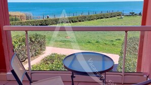 A balcony with a glass table and two chairs, overlooking a grassy area and the sea. - CAP CORNICHE - Studio cabine terrasse, clim, internet et parking (Sète)