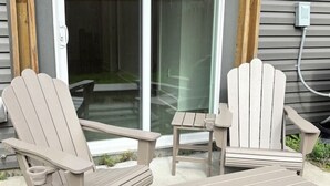 Ein Sitzbereich im Freien mit zwei Adirondack-Stühlen und einem kleinen Tisch.