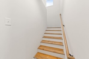 A staircase with wooden steps and a handrail, leading to a landing with a small window.