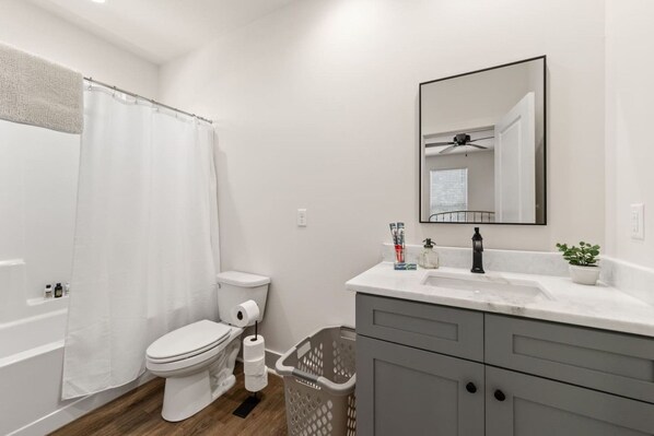 A modern bathroom with a toilet, shower, and sink.
