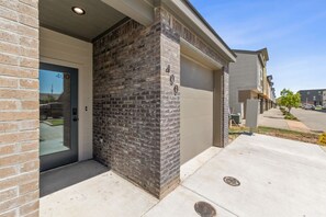 A residential building with a brick facade, a garage door, and a clear sky.