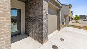Un immeuble résidentiel à la façade en briques, avec une porte de garage, et un ciel dégagé.