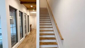 A staircase with wooden steps and white walls, leading to a room with a door.