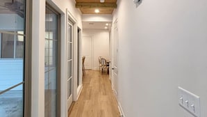 A narrow hallway with wooden flooring and a sloped ceiling.