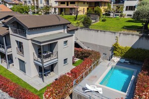 Ein modernes, zweistöckiges Haus mit Schwimmbad, Balkon und einem gepflegten Garten.