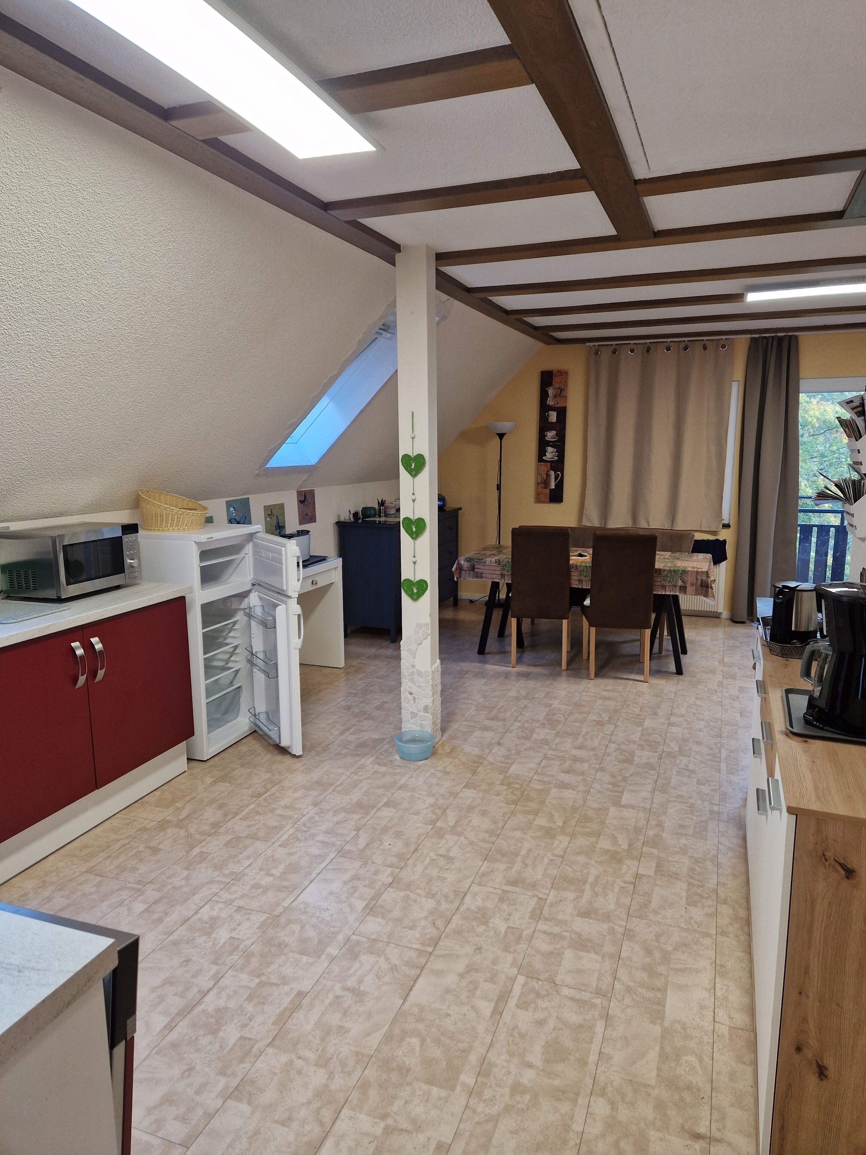 Eine kompakte Küche mit Mikrowelle, Kühlschrank und einem Essbereich mit Tisch und Stühlen.