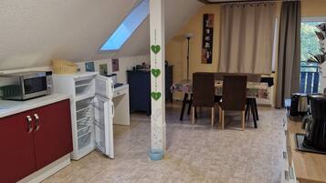 Eine kompakte Küche mit Mikrowelle, Kühlschrank und einem Essbereich mit Tisch und Stühlen.