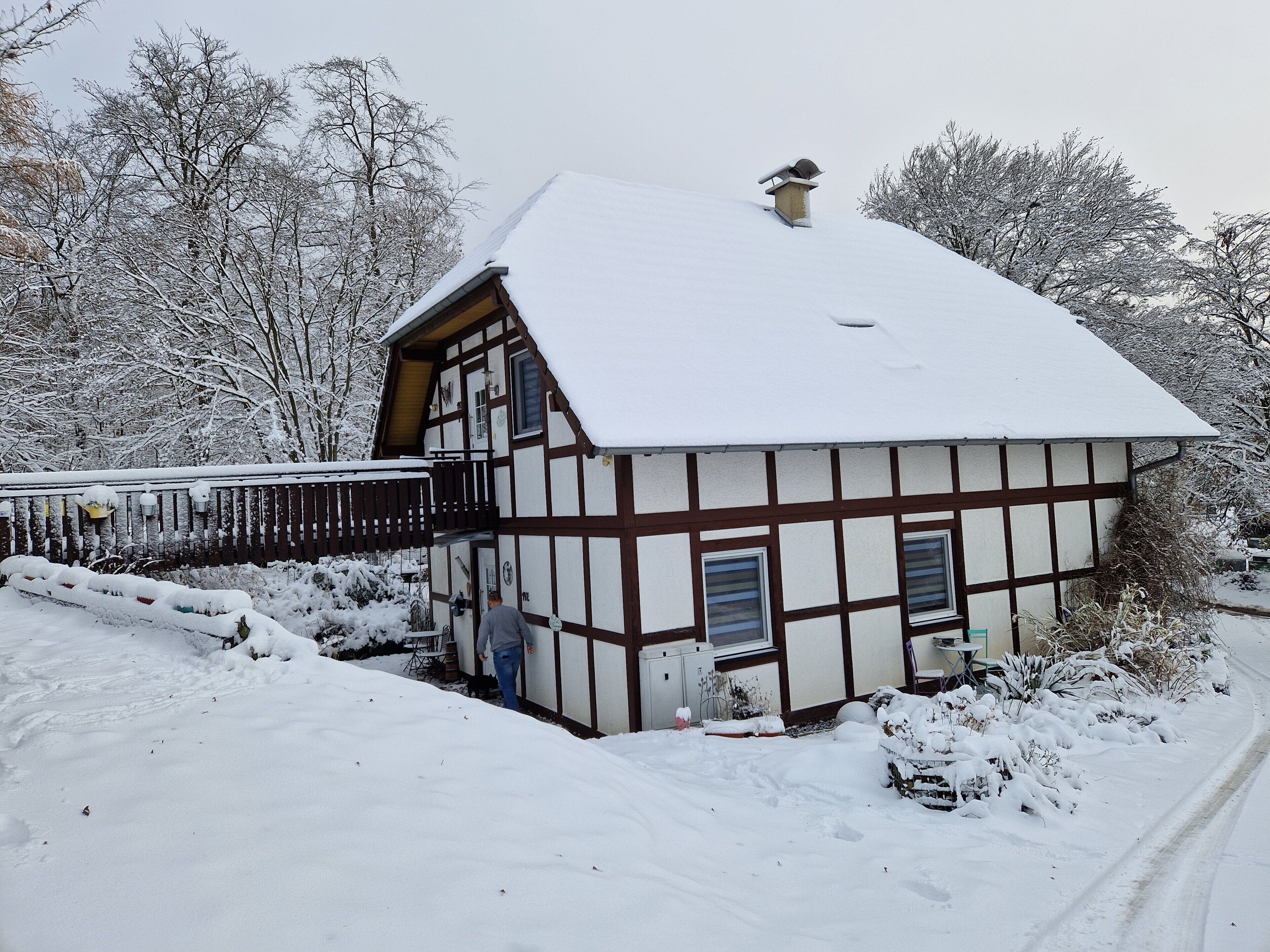 Ein traditionelles Fachwerkhäuschen mit verschneitem Dach und einem Holzbalkon.
