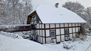 Ein traditionelles Fachwerkhäuschen mit verschneitem Dach und einem Holzbalkon.