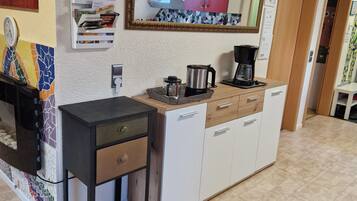 Eine moderne Küche mit Fliesenboden, einer Kaffeemaschine, einem Wasserkocher und einer Futterstelle für Haustiere.