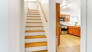 A staircase leading to a kitchen with wooden cabinets and a microwave. - 13 Mi to Downtown Detroit: Bright Home (Dearborn)