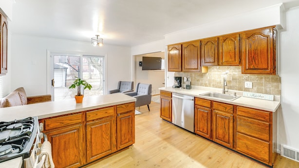 A kitchen with wooden cabinets, a central island, and a built-in dishwasher. - 13 Mi to Downtown Detroit: Bright Home (Dearborn)