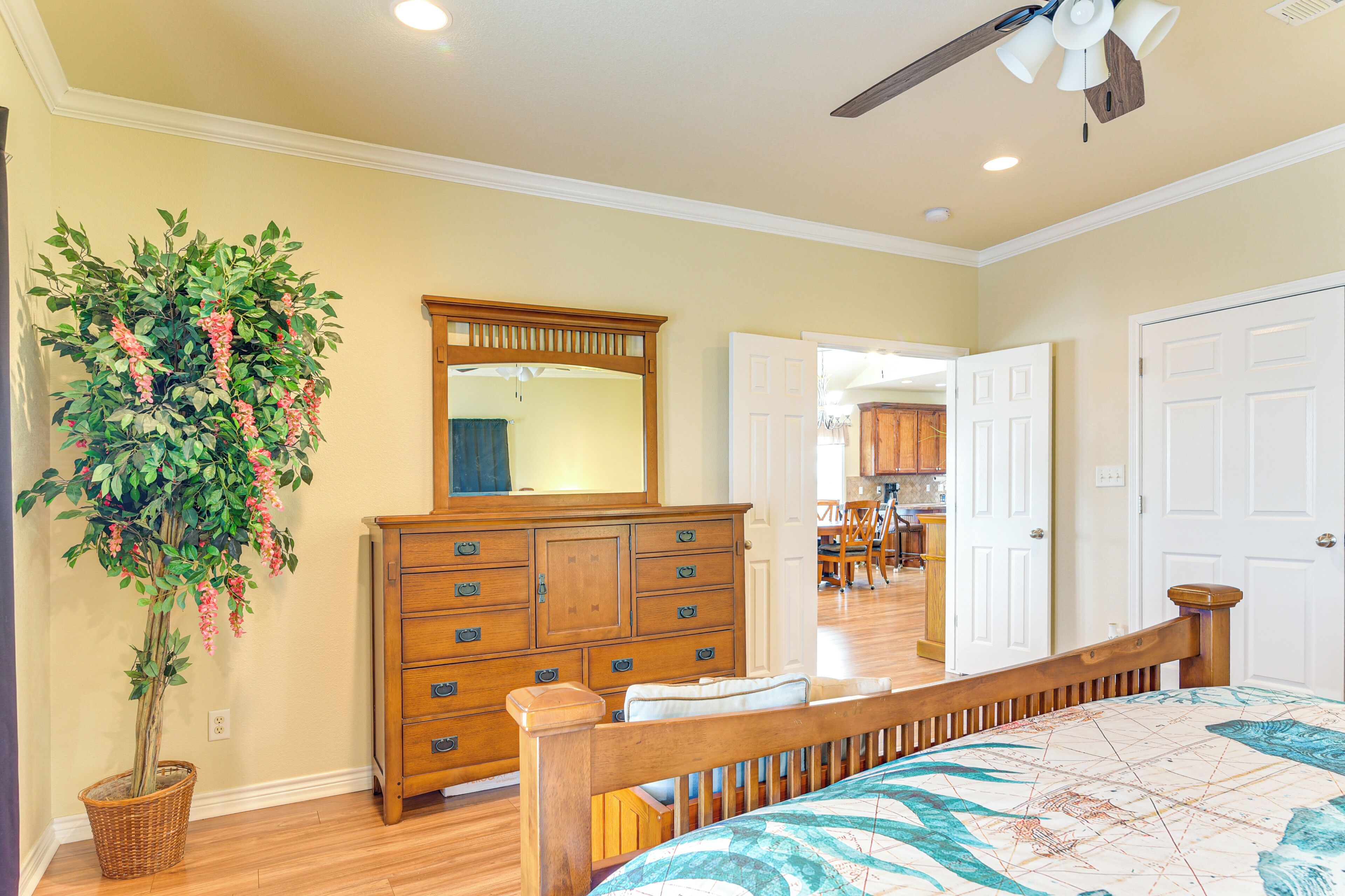 A bedroom with a wooden bed, dresser, and a large mirror.