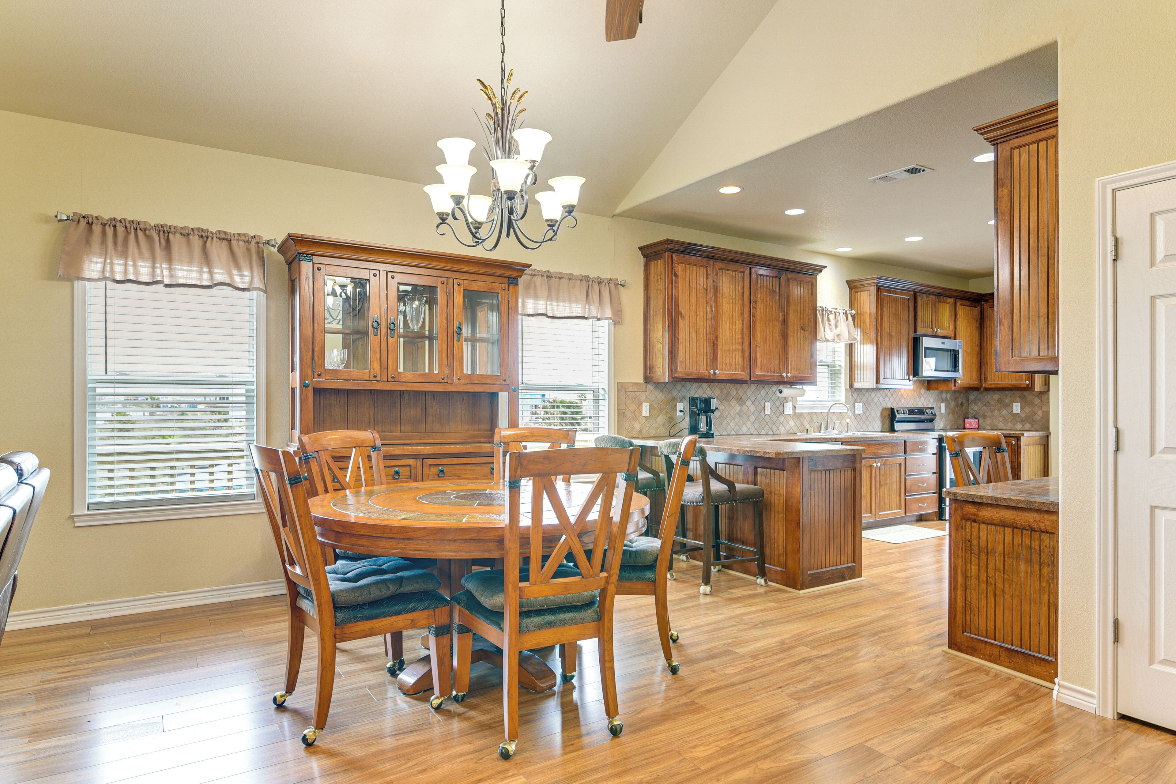 A spacious kitchen with wooden cabinets, a dining area with a round table and chairs, and a central island.