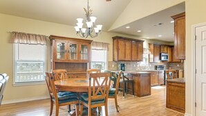 A spacious kitchen with wooden cabinets, a dining area with a round table and chairs, and a central island.