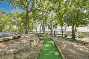 Un parcours de golf avec un fairway verdoyant, des arbres et un espace de stationnement, avec des bâtiments en arrière-plan.