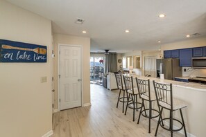 A kitchen with a bar area, wooden flooring, and a ceiling fan. - Table Rock Lake Condo w/ Sunrise Views & Pool (Kimberling City)