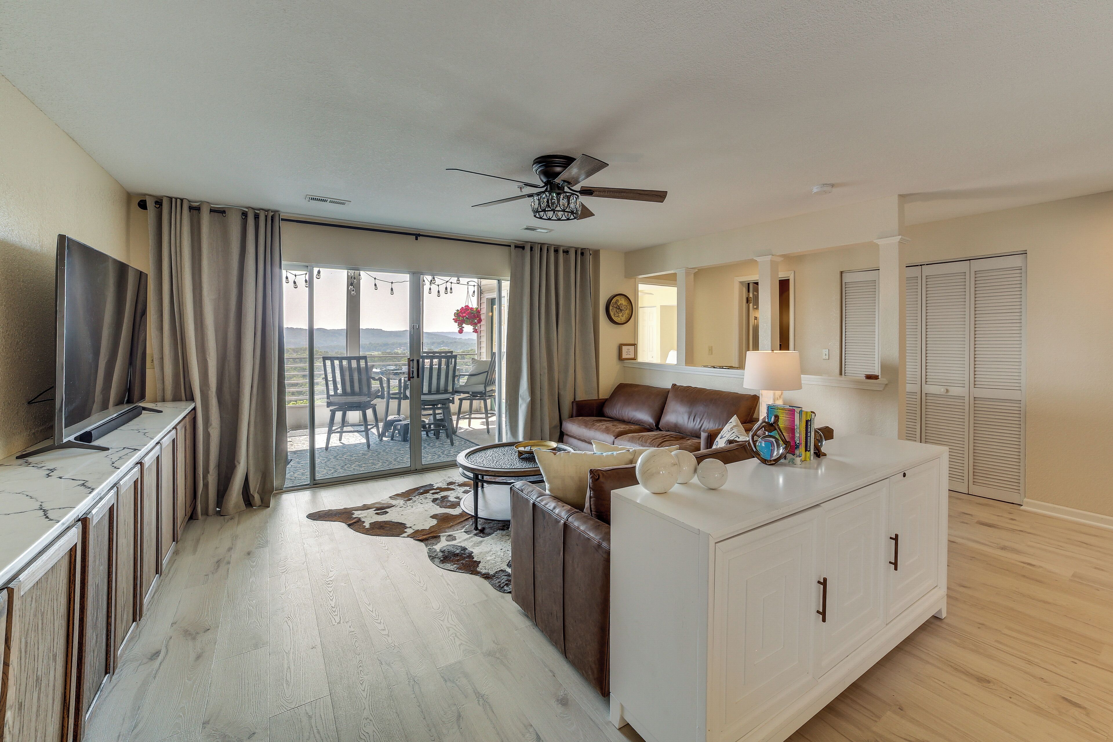 A modern living room with a television, sofa, coffee table, and a dining area with chairs and a table.