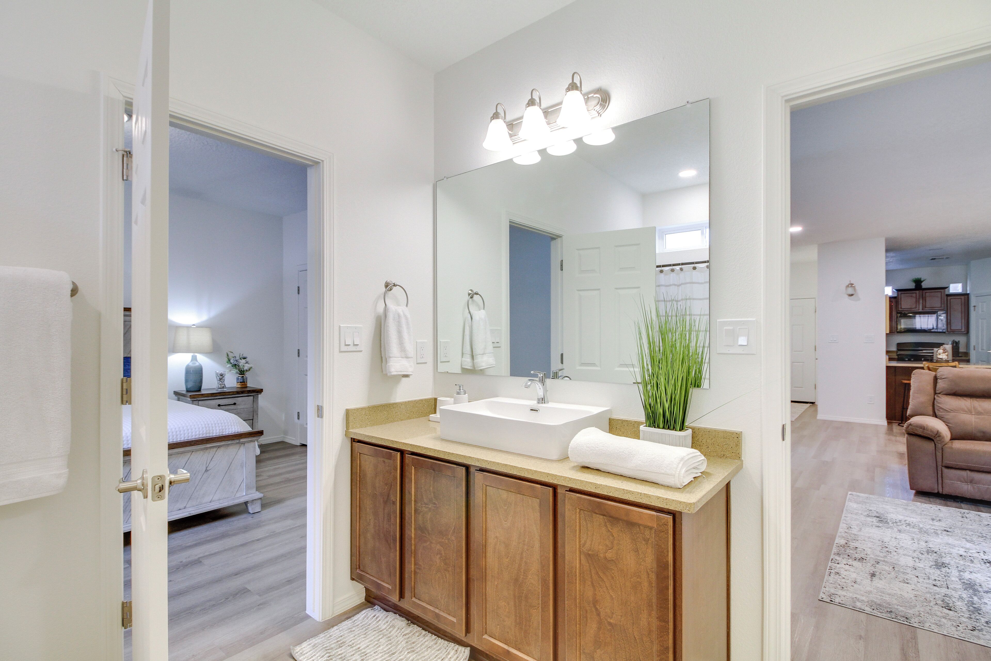 A modern bathroom with a large mirror, wooden vanity, and a sink.