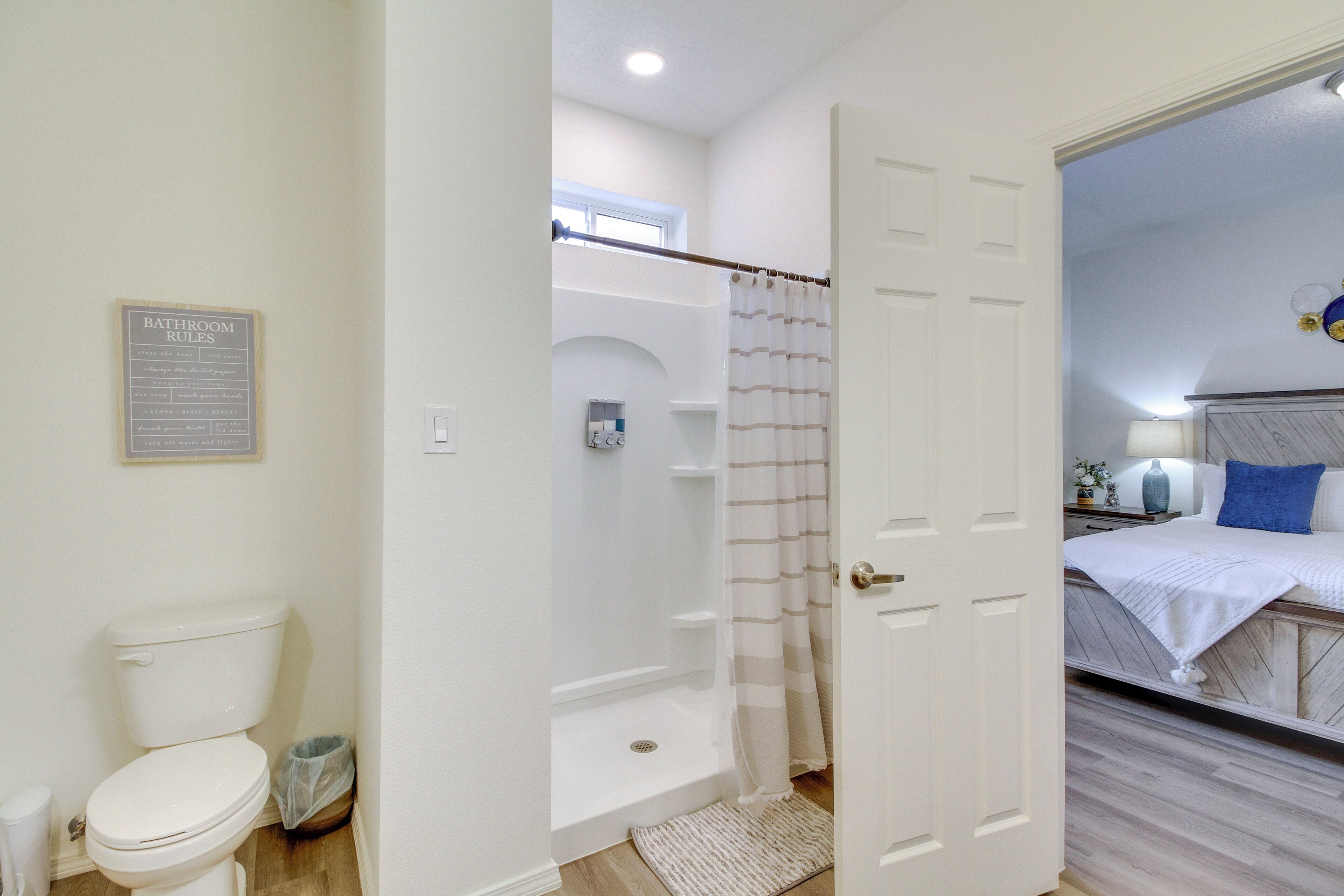 A bathroom with a toilet, shower, and a sign listing bathroom rules.