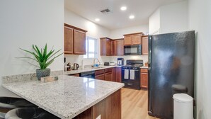 A modern kitchen with granite countertops, wooden cabinets, a stainless steel refrigerator, and a built-in oven. - 3 Mi to Old Town: Albuquerque Townhome w/ Yard! (Albuquerque)