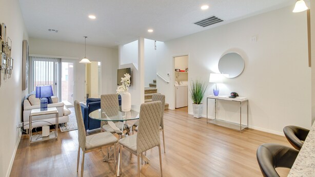 A modern living room with a glass coffee table, beige chairs, a blue sofa, and a dining area with a glass table and chairs. - 3 Mi to Old Town: Albuquerque Townhome w/ Yard! (Albuquerque)
