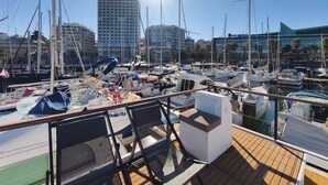 A marina with multiple boats docked, a clear sky, and buildings in the background. - Exclusive Boat in Vigo Marina | Private Terrace over the Sea (Vigo)