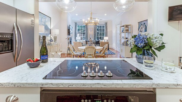 A modern kitchen with a central island, stainless steel appliances, and a dining area with a chandelier.